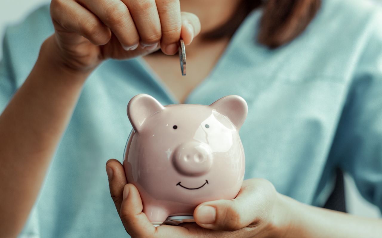 Eine Münze wird in ein Sparschwein gesteckt