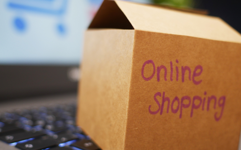Karton auf Laptop mit der Aufschrift Online Shopping