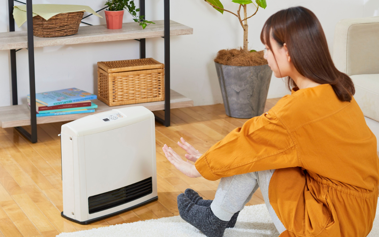 Frau sitzt vorm Heizgerät