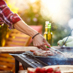 Im Sommer ist jemand am grillen. Würstchen und Gemüse liegen auf dem Grill
